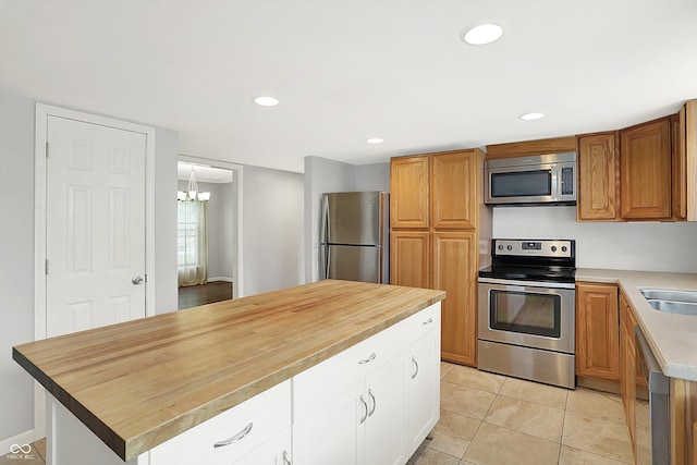 6838 Five Points Rd, Indianapolis, IN 46259 - kitchen with stainless steel appliances, a chandelier, light tile patterned flooring, white cabinets, and a sink