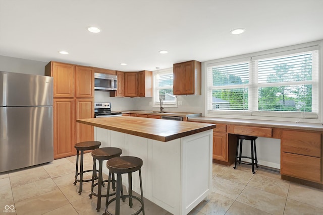 6838 Five Points Rd, Indianapolis, IN 46259 - kitchen with appliances with stainless steel finishes, butcher block counters, a sink, a breakfast bar, and light tile patterned flooring