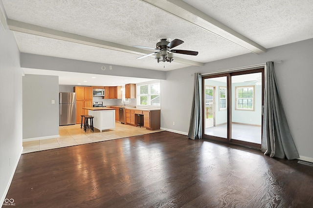 6838 Five Points Rd, Indianapolis, IN 46259 - unfurnished living room featuring light wood-type flooring, baseboards, ceiling fan, a textured ceiling, and beamed ceiling