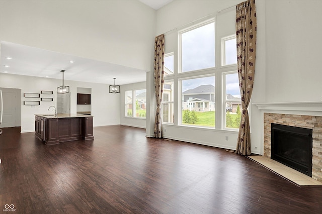 7046 Allegiance Ct, Indianapolis, IN 46259 - unfurnished living room with dark wood-style floors, a sink, a stone fireplace, baseboards, and recessed lighting