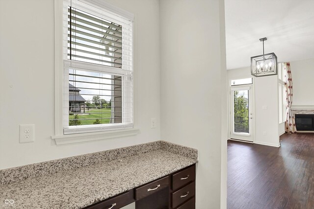 7046 Allegiance Ct, Indianapolis, IN 46259 - kitchen with dark brown cabinetry, dark wood-style flooring, a chandelier, light stone countertops, and pendant lighting