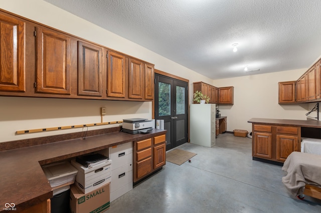 2411 N County Road 500 W, Muncie, IN 47304 - kitchen with dark countertops, concrete flooring, brown cabinets, a textured ceiling, and built in study area