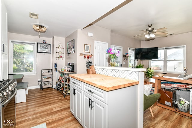 635 E 10th St, Indianapolis, IN 46202 - kitchen with wooden counters, stainless steel range with gas stovetop, white cabinets, light wood-style flooring, and a ceiling fan