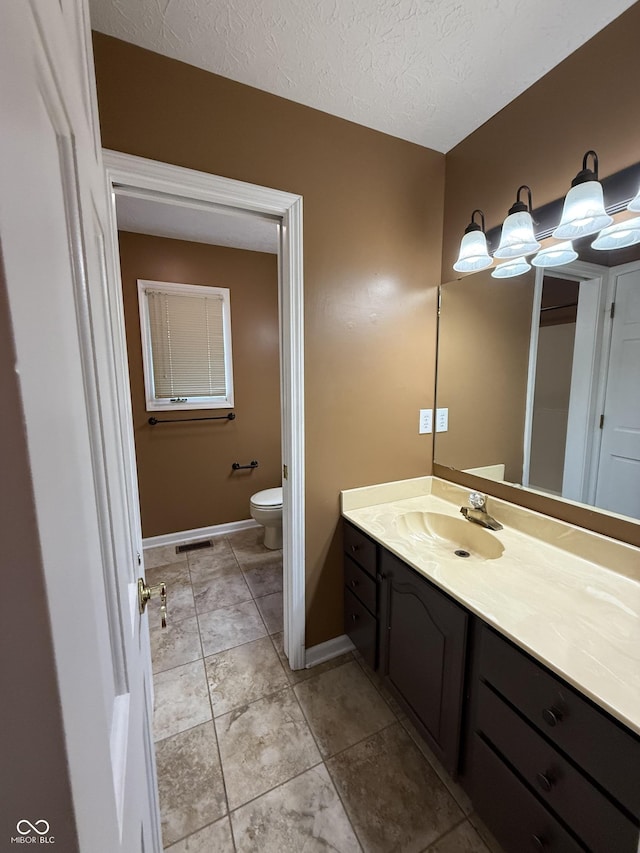 6609 N Tuxedo Ln, Indianapolis, IN 46220 - bathroom with toilet, vanity, baseboards, and a textured ceiling