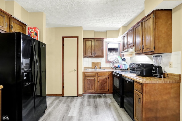 926 Brookside Ln, Plainfield, IN 46168 - kitchen featuring black appliances, light wood-style flooring, under cabinet range hood, brown cabinets, and a sink