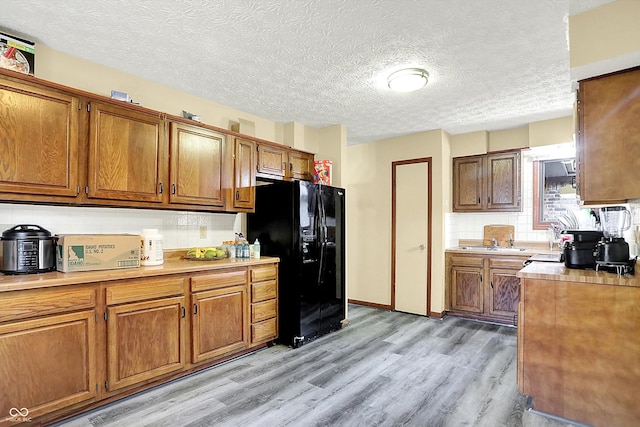 926 Brookside Ln, Plainfield, IN 46168 - kitchen featuring black fridge, brown cabinets, light countertops, light wood finished floors, and a textured ceiling