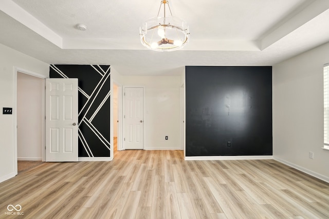 1454 Silver Pine Ln, Sheridan, IN 46069 - spare room featuring a raised ceiling, a chandelier, light wood finished floors, and baseboards
