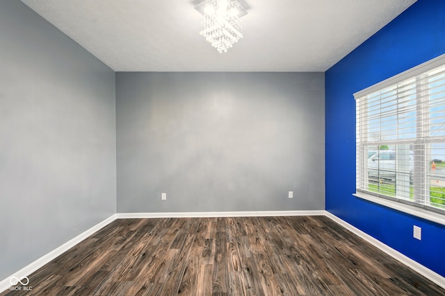 1454 Silver Pine Ln, Sheridan, IN 46069 - spare room with a chandelier, baseboards, and dark wood-style flooring