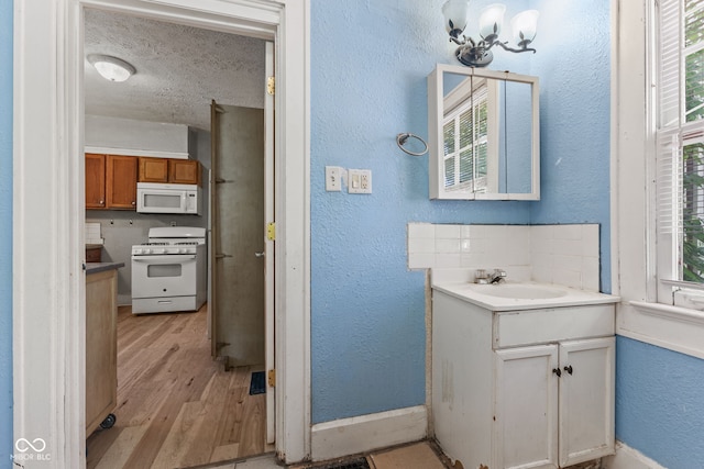3134 N College Ave, Indianapolis, IN 46205 - bathroom featuring wood finished floors, vanity, a textured wall, baseboards, and a textured ceiling