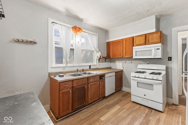 3134 N College Ave, Indianapolis, IN 46205 - kitchen with white appliances, brown cabinets, a sink, light wood-style floors, and a textured wall
