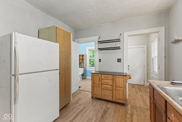 3134 N College Ave, Indianapolis, IN 46205 - kitchen featuring freestanding refrigerator, light wood finished floors, a sink, brown cabinetry, and a textured ceiling
