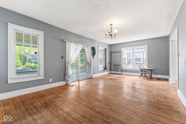 3134 N College Ave, Indianapolis, IN 46205 - unfurnished living room featuring a textured wall, a chandelier, a textured ceiling, wood finished floors, and baseboards