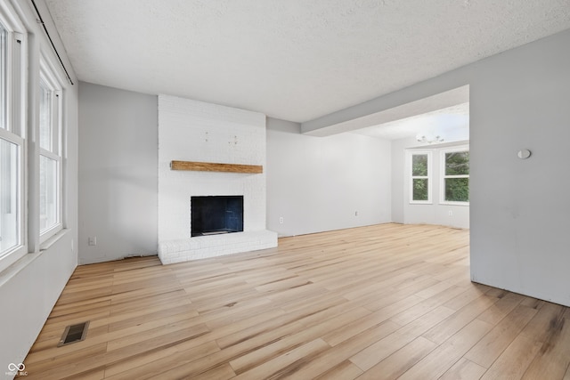 1826 Shorter Dr, Indianapolis, IN 46214 - unfurnished living room featuring wood finished floors, a brick fireplace, a chandelier, and a textured ceiling