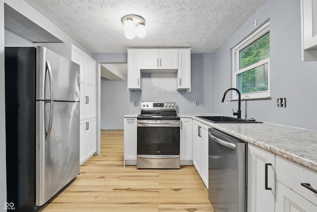 1826 Shorter Dr, Indianapolis, IN 46214 - kitchen featuring stainless steel appliances, a sink, light wood-style floors, white cabinets, and a textured ceiling