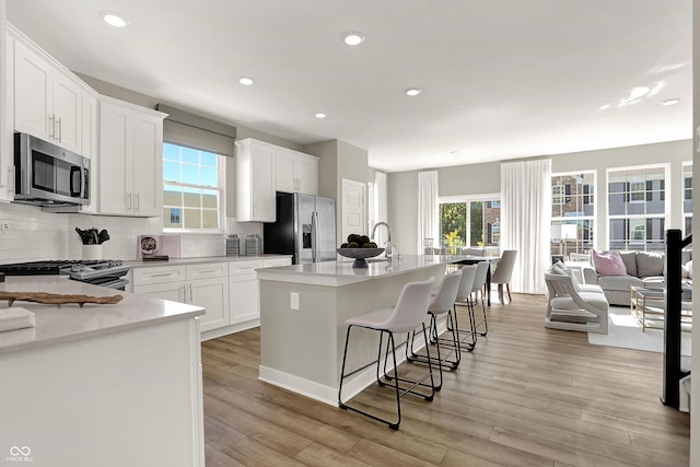 6702 Halsey St, Zionsville, IN 46077 - kitchen with stainless steel appliances, a breakfast bar, light wood finished floors, tasteful backsplash, and recessed lighting