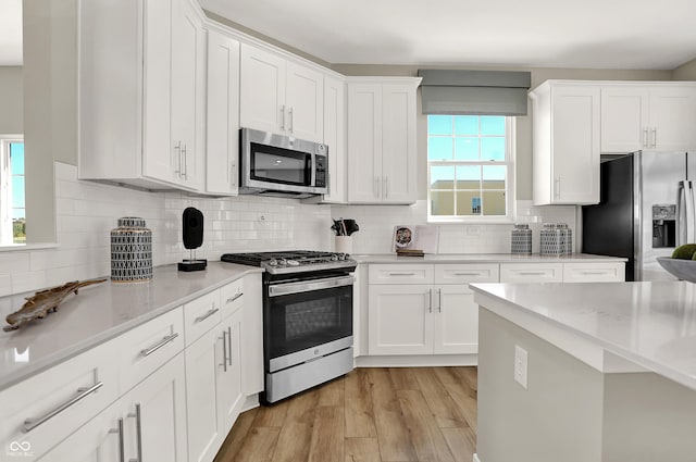 6702 Halsey St, Zionsville, IN 46077 - kitchen with appliances with stainless steel finishes, white cabinets, light wood finished floors, and tasteful backsplash
