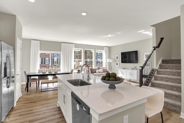 6702 Halsey St, Zionsville, IN 46077 - kitchen with stainless steel appliances, a sink, open floor plan, white cabinets, and light wood-style floors