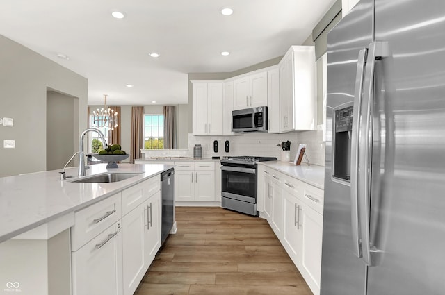 6702 Halsey St, Zionsville, IN 46077 - kitchen featuring appliances with stainless steel finishes, a sink, tasteful backsplash, a chandelier, and white cabinetry