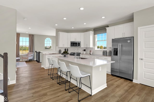 6702 Halsey St, Zionsville, IN 46077 - kitchen featuring appliances with stainless steel finishes, light wood-style floors, plenty of natural light, a kitchen island with sink, and recessed lighting