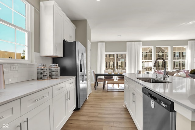 6702 Halsey St, Zionsville, IN 46077 - kitchen with stainless steel appliances, a sink, decorative backsplash, light wood-type flooring, and light countertops