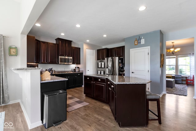 13485 Mancroft Dr, Fishers, IN 46037 - kitchen featuring appliances with stainless steel finishes, a chandelier, light wood-type flooring, a breakfast bar area, and dark brown cabinets