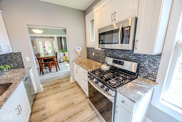 517 Bernard Ave, Indianapolis, IN 46208 - kitchen with appliances with stainless steel finishes, light wood-style floors, white cabinetry, and backsplash
