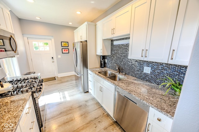 517 Bernard Ave, Indianapolis, IN 46208 - kitchen featuring appliances with stainless steel finishes, a sink, light wood finished floors, decorative backsplash, and light stone countertops