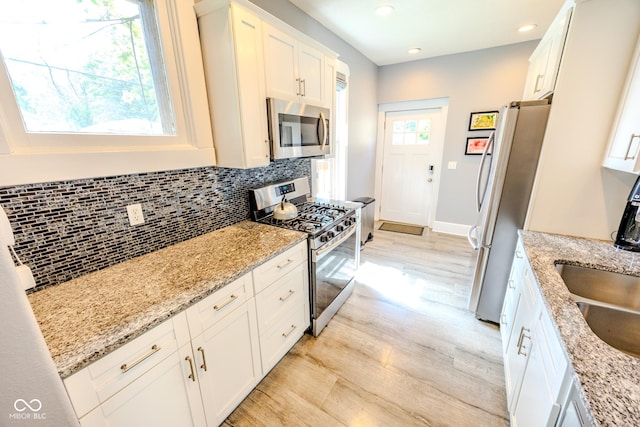 517 Bernard Ave, Indianapolis, IN 46208 - kitchen with stainless steel appliances, decorative backsplash, white cabinets, light wood-style floors, and recessed lighting