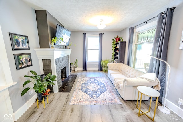 517 Bernard Ave, Indianapolis, IN 46208 - living room featuring baseboards, wood finished floors, a brick fireplace, and a textured ceiling