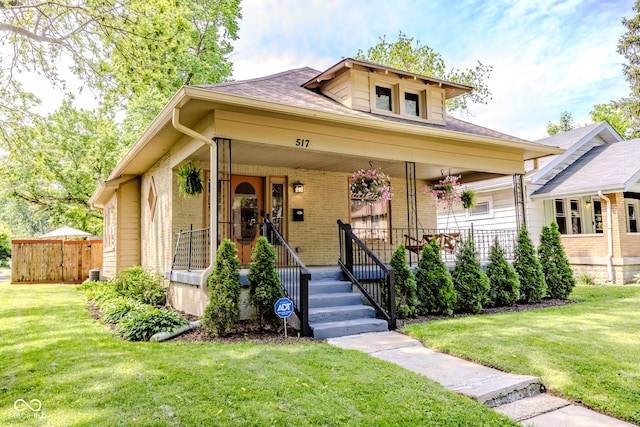 517 Bernard Ave, Indianapolis, IN 46208 - view of front of home with covered porch, brick siding, a front yard, and roof with shingles