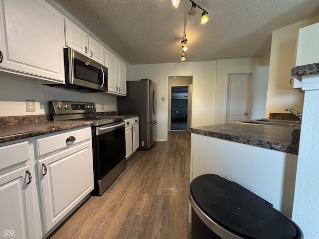 5502 Floating Leaf Dr, Indianapolis, IN 46237 - kitchen with stainless steel appliances, a textured ceiling, dark countertops, white cabinetry, and dark wood-style flooring