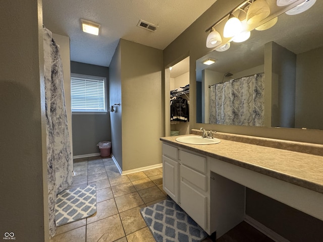 5502 Floating Leaf Dr, Indianapolis, IN 46237 - bathroom featuring vanity, tile patterned flooring, baseboards, a textured ceiling, and a spacious closet