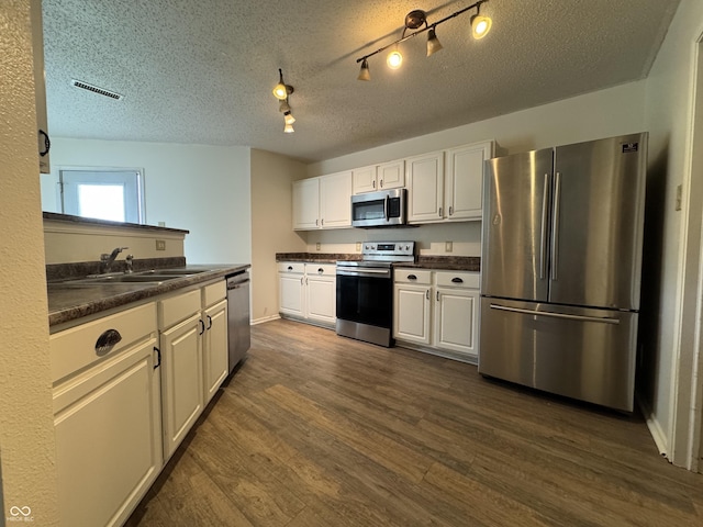 5502 Floating Leaf Dr, Indianapolis, IN 46237 - kitchen featuring appliances with stainless steel finishes, a sink, dark countertops, dark wood-style floors, and a textured ceiling