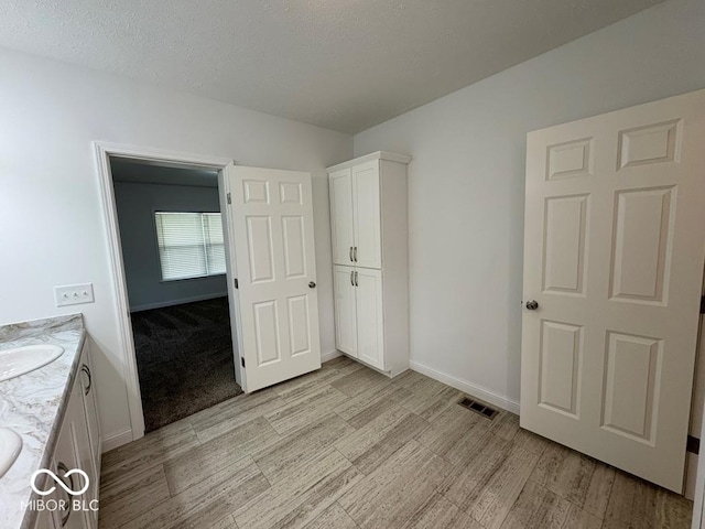 844 Ben Franklin St, Cloverdale, IN 46120 - unfurnished bedroom with light wood-style floors, baseboards, a sink, and a textured ceiling