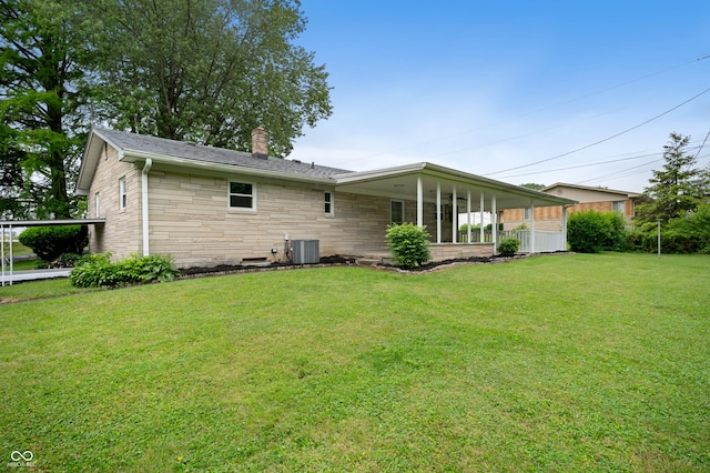 7482 W US Highway 40, Indianapolis, IN 46229 - rear view of property featuring a chimney, a yard, stone siding, and central AC unit