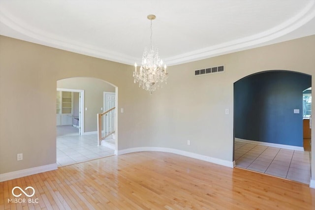 11575 Freeport Dr, Carmel, IN 46032 - spare room featuring arched walkways, light wood finished floors, a chandelier, and stairs