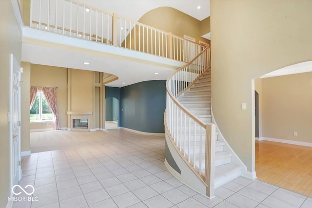 11575 Freeport Dr, Carmel, IN 46032 - stairs with arched walkways, a high ceiling, tile patterned floors, and baseboards