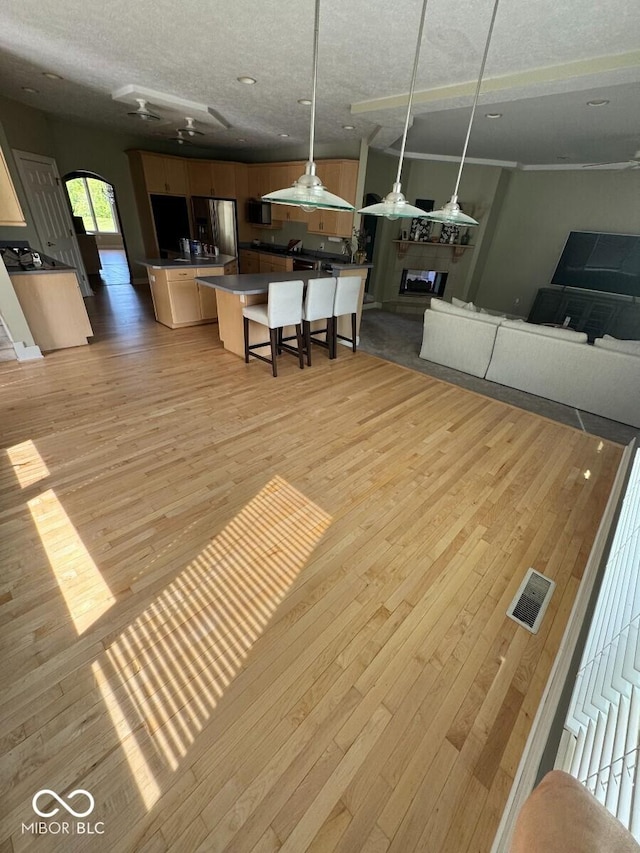 11575 Freeport Dr, Carmel, IN 46032 - living area featuring light wood-style flooring, arched walkways, a textured ceiling, and a ceiling fan