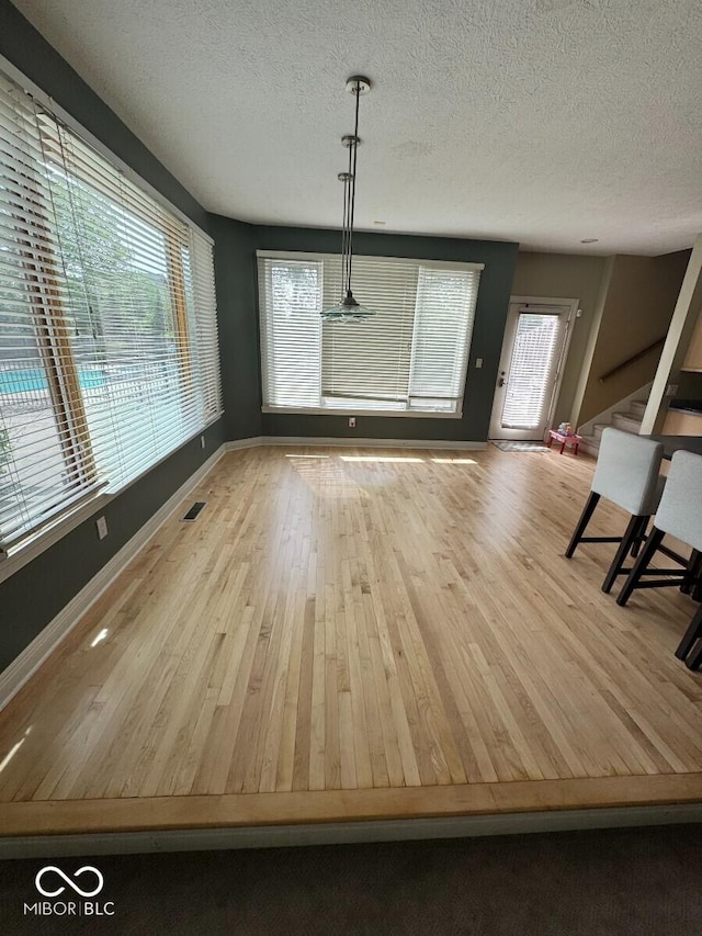 11575 Freeport Dr, Carmel, IN 46032 - unfurnished dining area with a textured ceiling, wood finished floors, and baseboards
