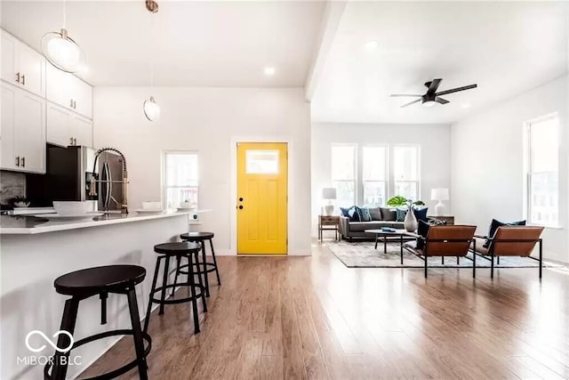 918 S State Ave, Indianapolis, IN 46203 - kitchen with a ceiling fan, a breakfast bar, white cabinetry, light wood-type flooring, and light countertops