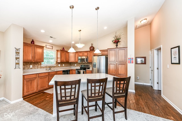 11692 Seven Oaks Dr, Fishers, IN 46038 - kitchen with stainless steel appliances, a sink, light countertops, brown cabinets, and high vaulted ceiling