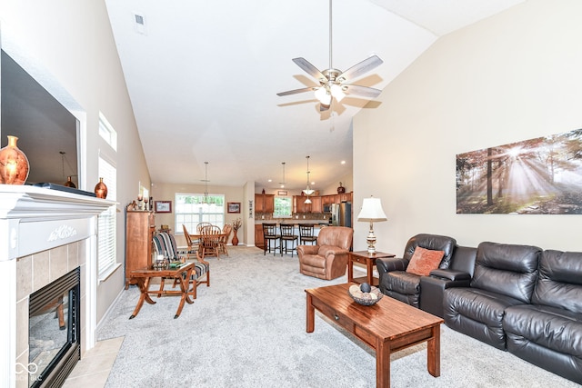 11692 Seven Oaks Dr, Fishers, IN 46038 - living room featuring a ceiling fan, a tiled fireplace, high vaulted ceiling, and light carpet