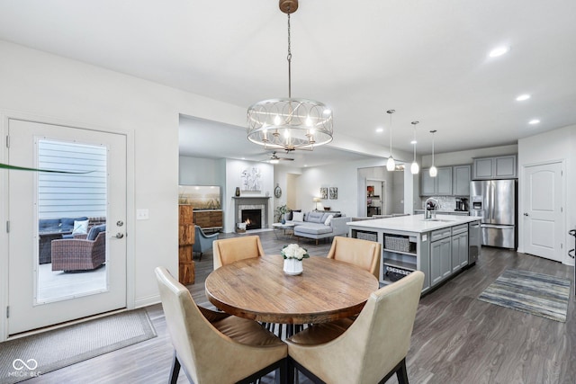 14458 Carlow Run, Carmel, IN 46074 - dining room featuring a chandelier, dark wood-style flooring, recessed lighting, and a lit fireplace
