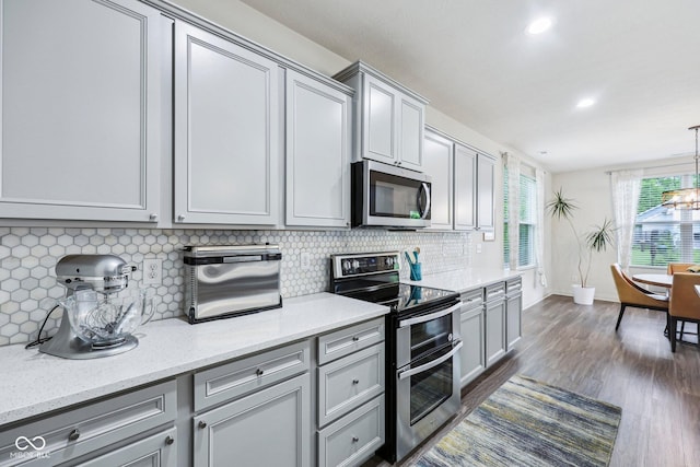 14458 Carlow Run, Carmel, IN 46074 - kitchen featuring appliances with stainless steel finishes, gray cabinetry, tasteful backsplash, dark wood-style flooring, and baseboards