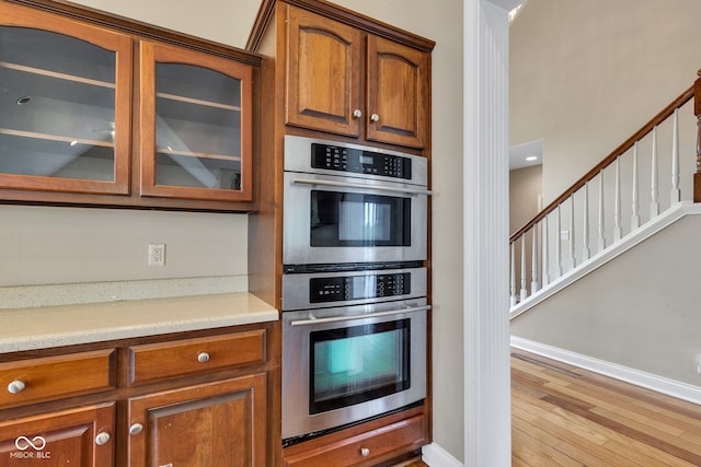 6610 Royal Oakland Dr, Indianapolis, IN 46236 - kitchen with double oven, baseboards, glass insert cabinets, and brown cabinets