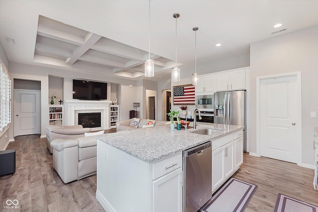 15593 Marsden Dr, Westfield, IN 46074 - kitchen featuring appliances with stainless steel finishes, light wood-type flooring, an island with sink, beamed ceiling, and white cabinetry