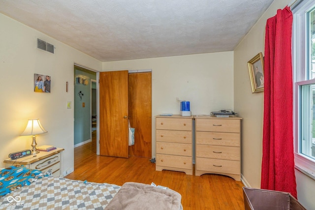 2445 S Bolton Ave, Indianapolis, IN 46203 - bedroom featuring wood finished floors, multiple windows, and a textured ceiling