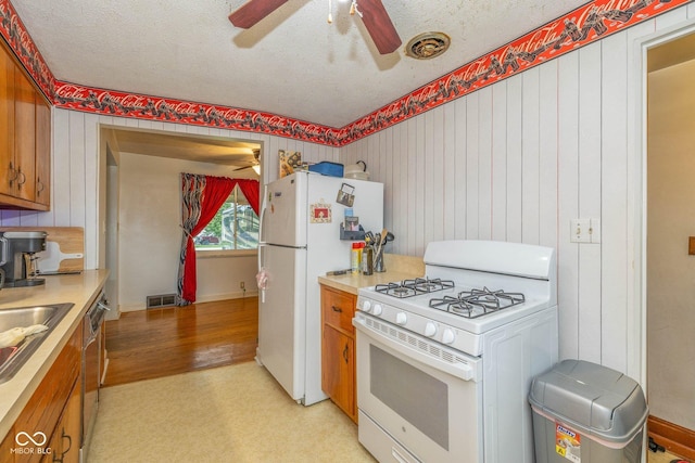 2445 S Bolton Ave, Indianapolis, IN 46203 - kitchen featuring white appliances, ceiling fan, brown cabinets, light countertops, and a textured ceiling