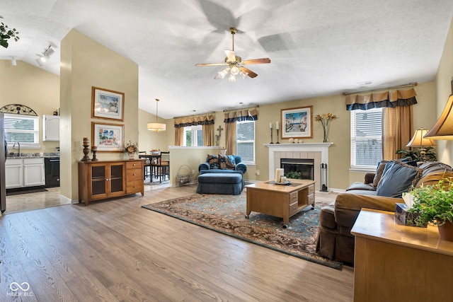 2163 Bradford Trace Blvd, Indianapolis, IN 46229 - living area with ceiling fan, light wood-style floors, lofted ceiling, a fireplace, and a textured ceiling