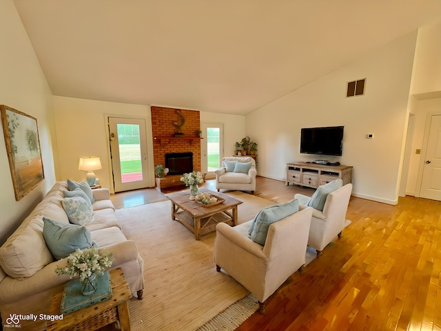67 Bittersweet Ct, Seymour, IN 47274 - living room featuring light wood-type flooring, high vaulted ceiling, a brick fireplace, and baseboards